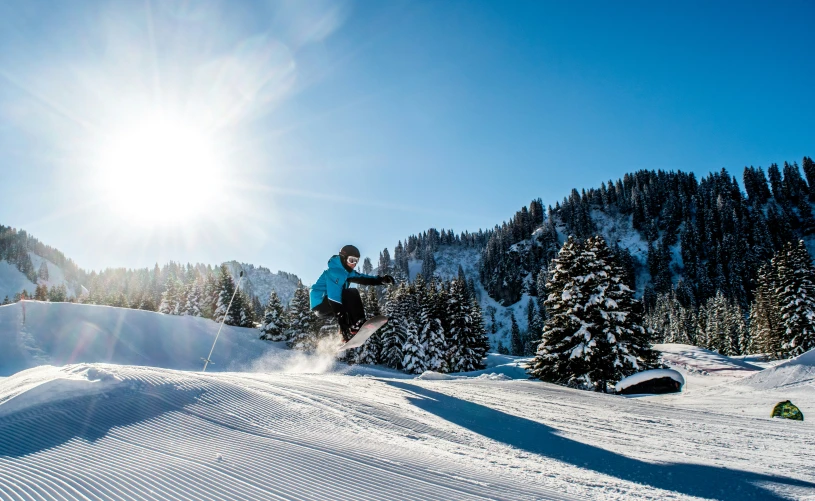 a snowboarder going downhill while jumping over the slopes