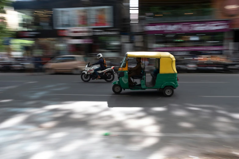 the man is driving the small vehicle down the road