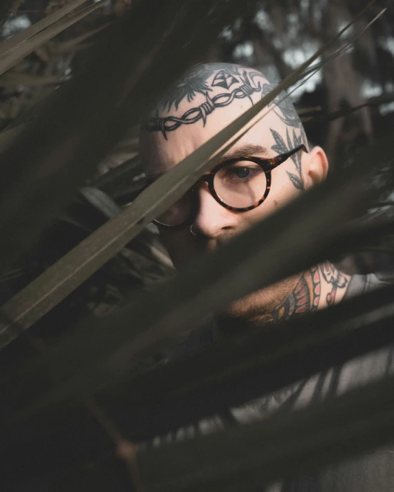 a man with eyeglasses and tattoos covering his face