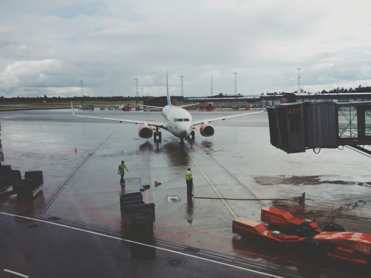 an airplane is parked on the runway, near people and luggage