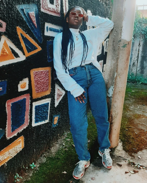 a woman leaning against the wall in a blue shirt