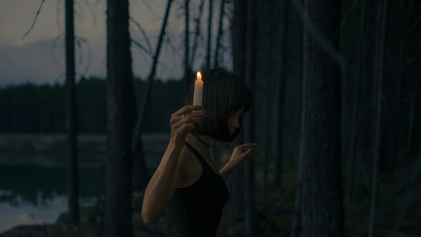 a person holding a candle in the woods