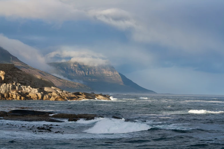 a man is standing on the shore next to a rock formation