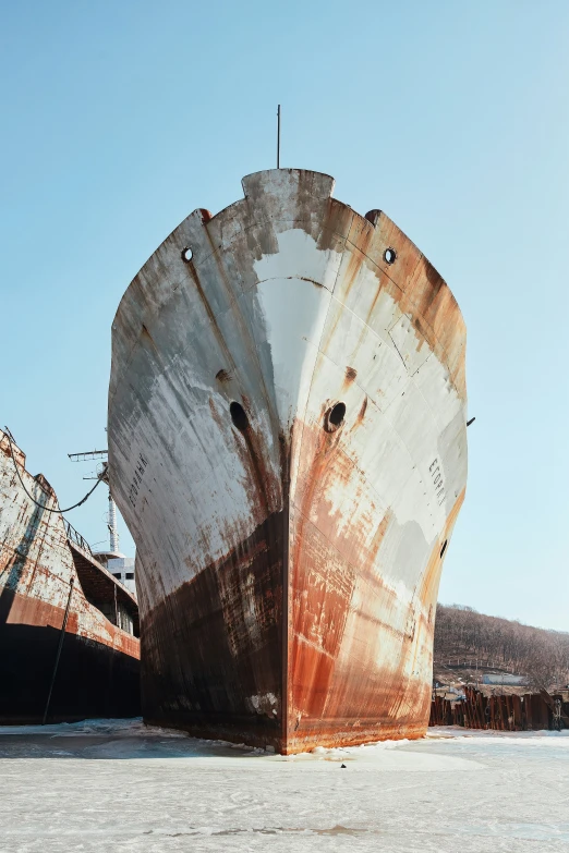 two rusty ships are docked next to each other