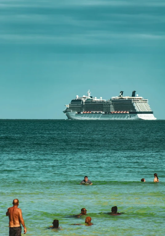 people laying in the ocean on their stomachs watching the ship