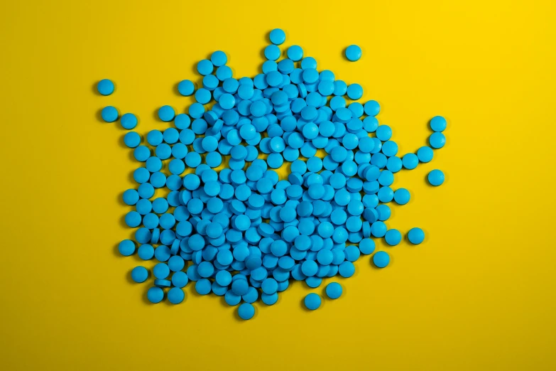 pills are scattered over a yellow surface with bright blue colors