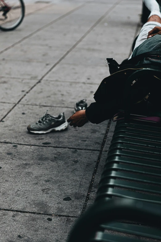 a man that is sitting down next to a bench