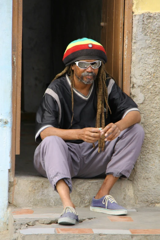 the man in his home is wearing a beanie and dreadlocks