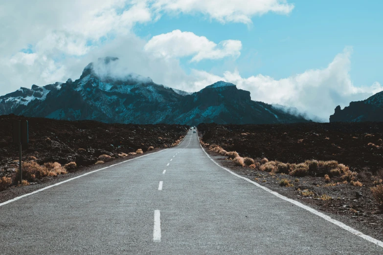 a empty road is in front of a mountain range