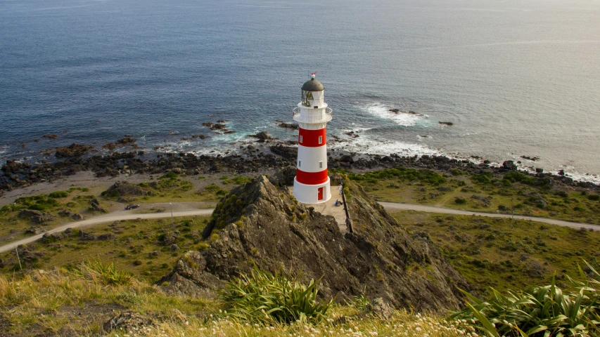 a red and white lighthouse sitting on top of a mountain