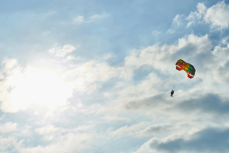 a parasailer flying in the blue cloudy sky