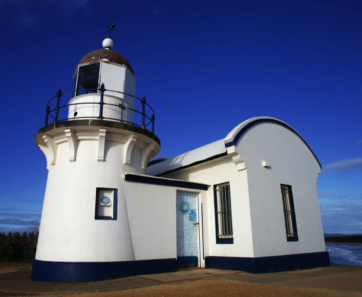 the white building has a black door and has a brown roof