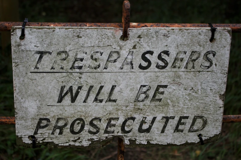 a rusted up sign reading trespassers will be protected