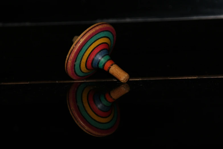 two colorful toys resting on black surface with reflections