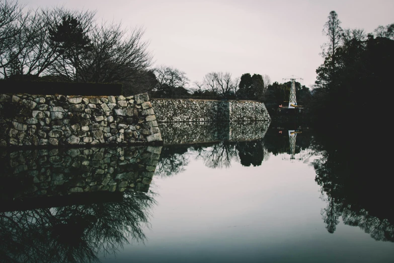 the water is reflecting the rock fence around it