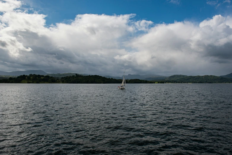 a sail boat on water under cloudy skies