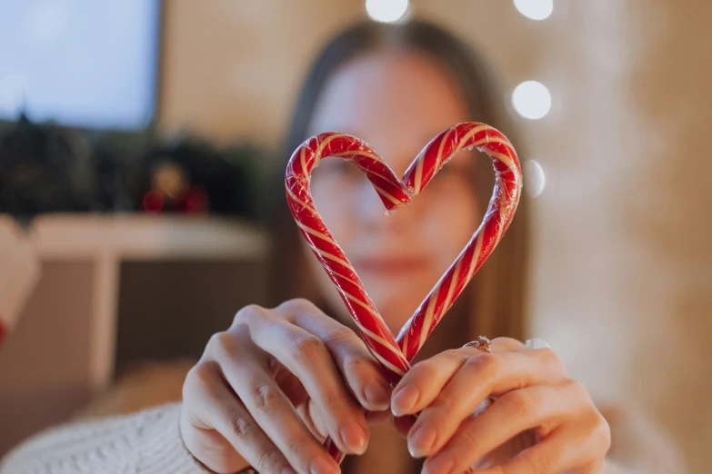 a woman holds two candy canes in her hands