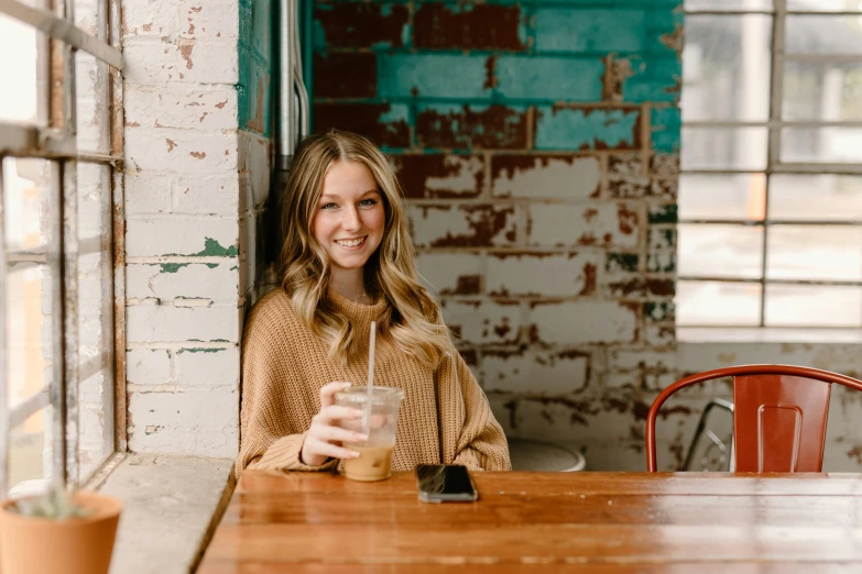 a woman smiles while drinking from a glass