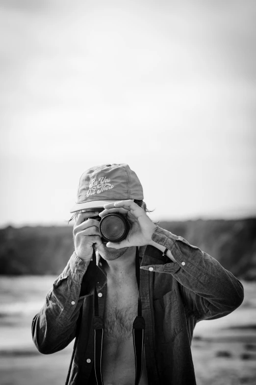 a man standing next to a large body of water holding a camera up