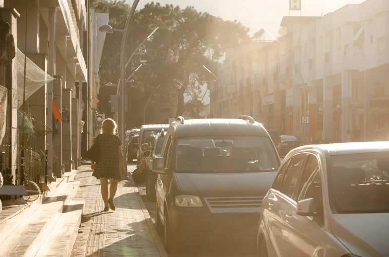 a woman walks in the sun while traffic passes her
