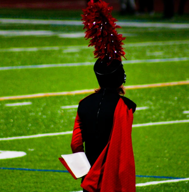 a girl with a red feather hat stands on the field