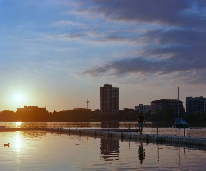 the sun is setting over the water by the city skyline