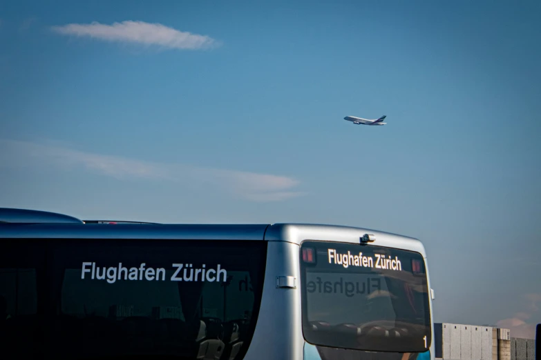 a bus is seen near the large airplane flying above