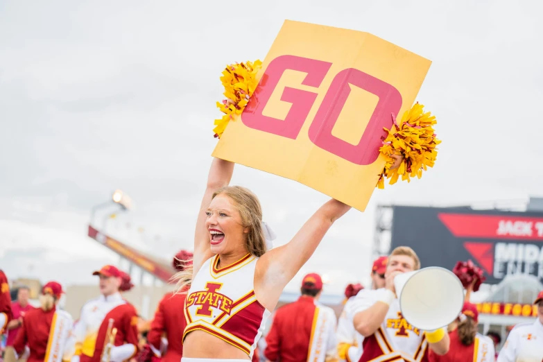 a cheerleader holding a flag up and gesturing at the crowd