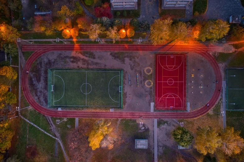 an aerial view of a park with a field and basketball courts at night