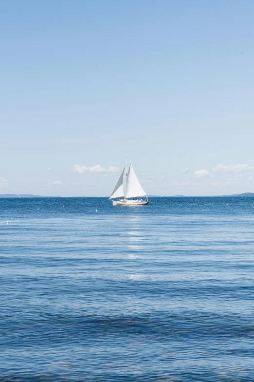 an empty sailboat floats on a clear, blue body of water