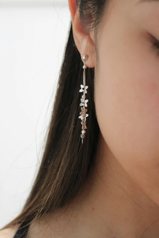 a woman wearing earrings with white flowers and clear beads