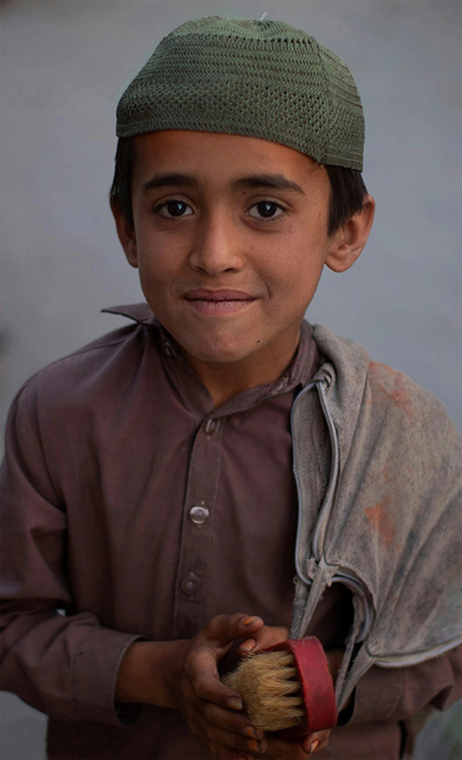 a boy with a hat and a hat on standing in front of his house