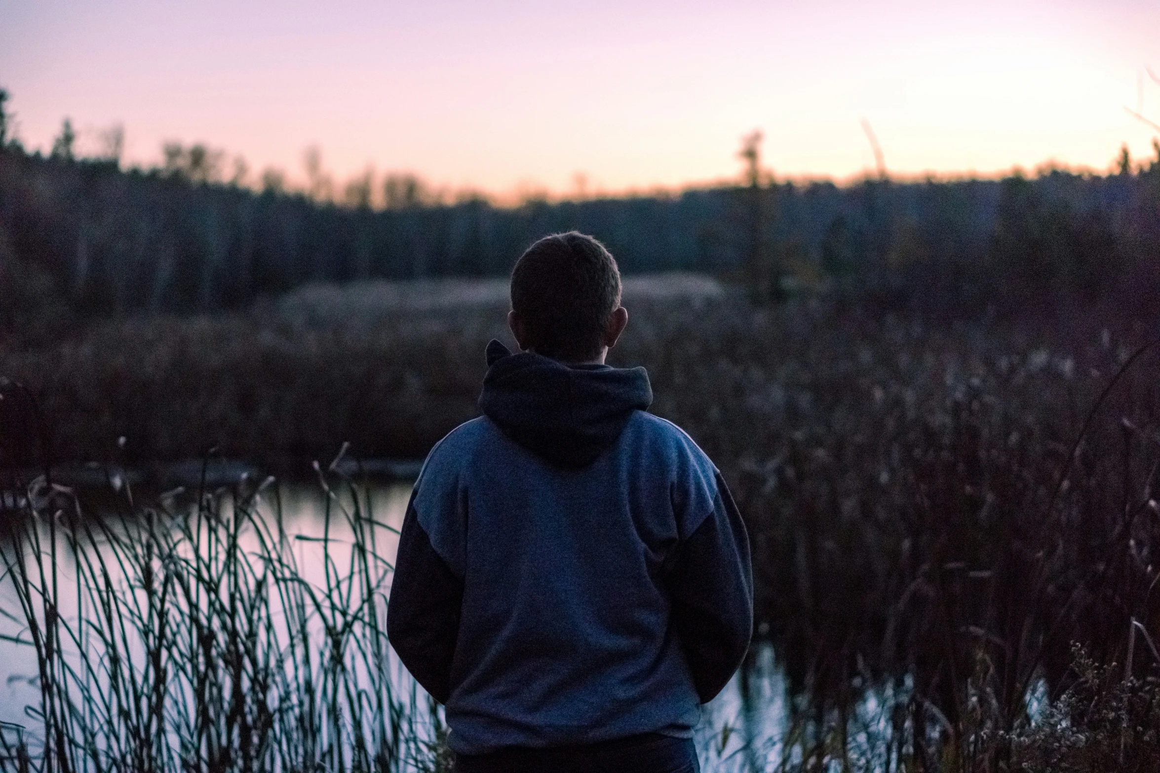 a man walking past a lake at sunset