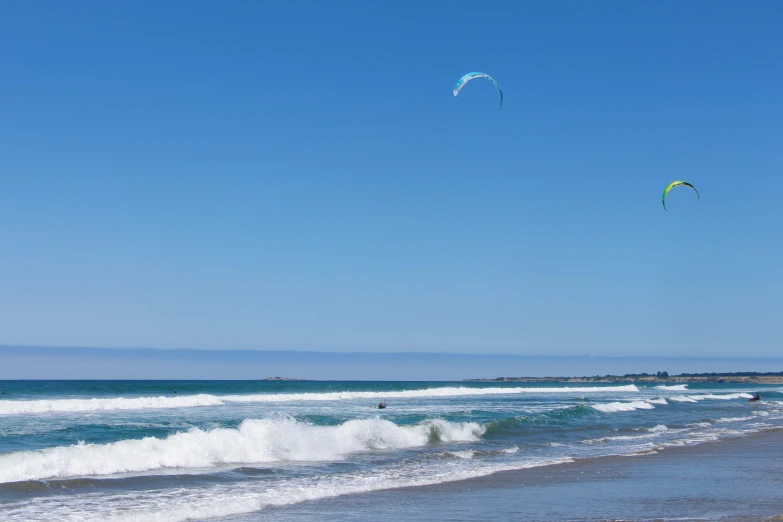 kites are flying over the waves in the ocean