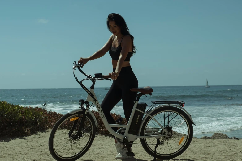 a pretty lady posing with her bike by the beach