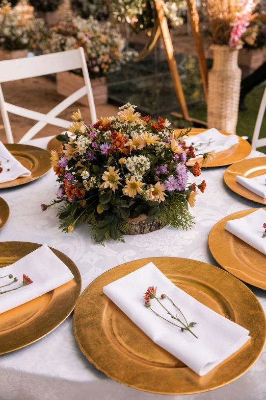 the table is set with white plates, napkins and flowers