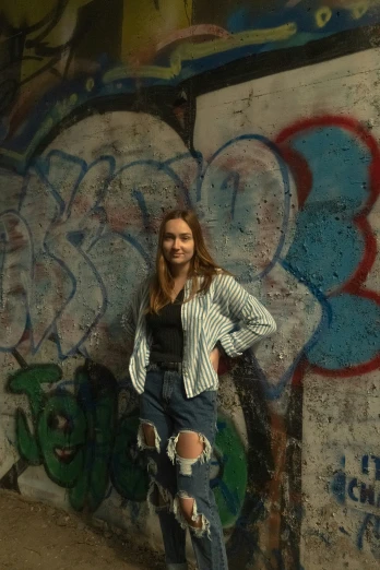 the girl is posing with her skateboard by graffiti wall