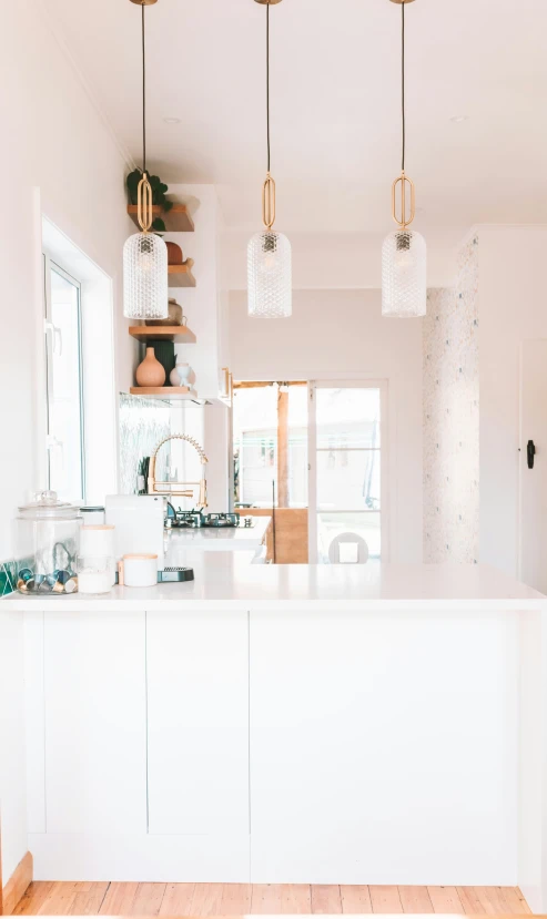 a bright, white kitchen with island and hanging lights