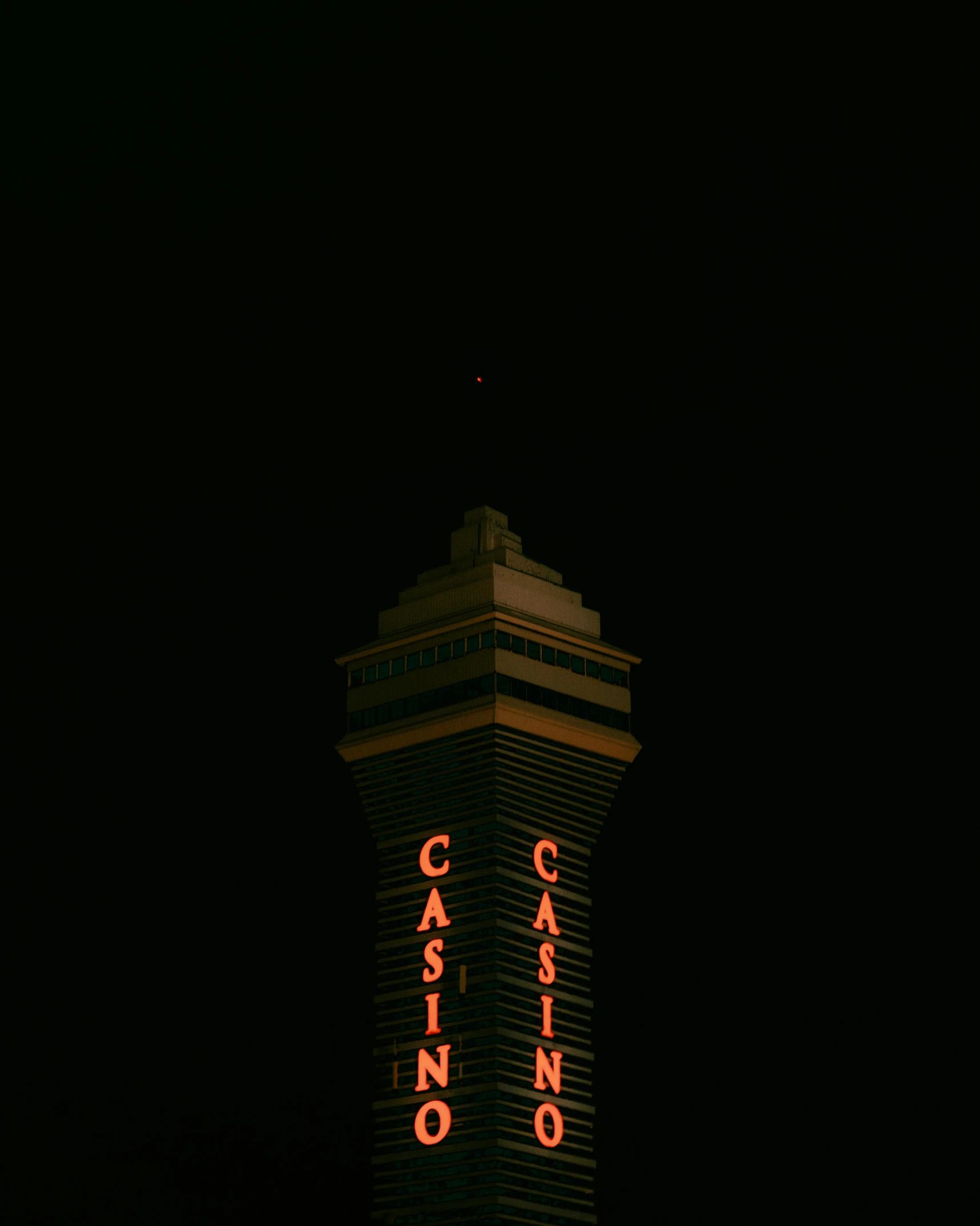 a casino tower in the dark with neon signs