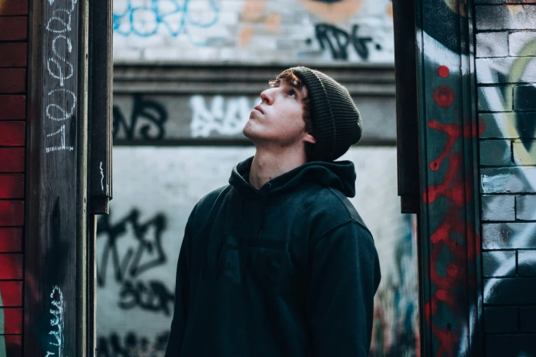 a man in black jacket looking up at soing on wall