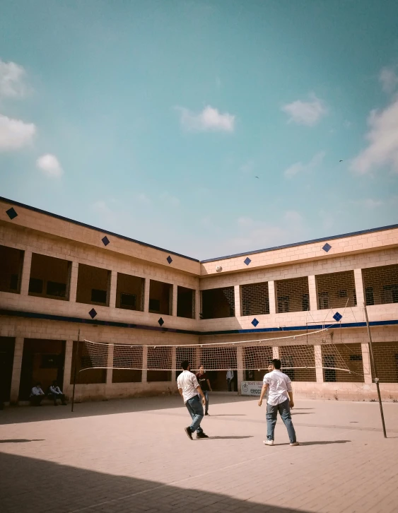 a couple of guys playing tennis in a courtyard