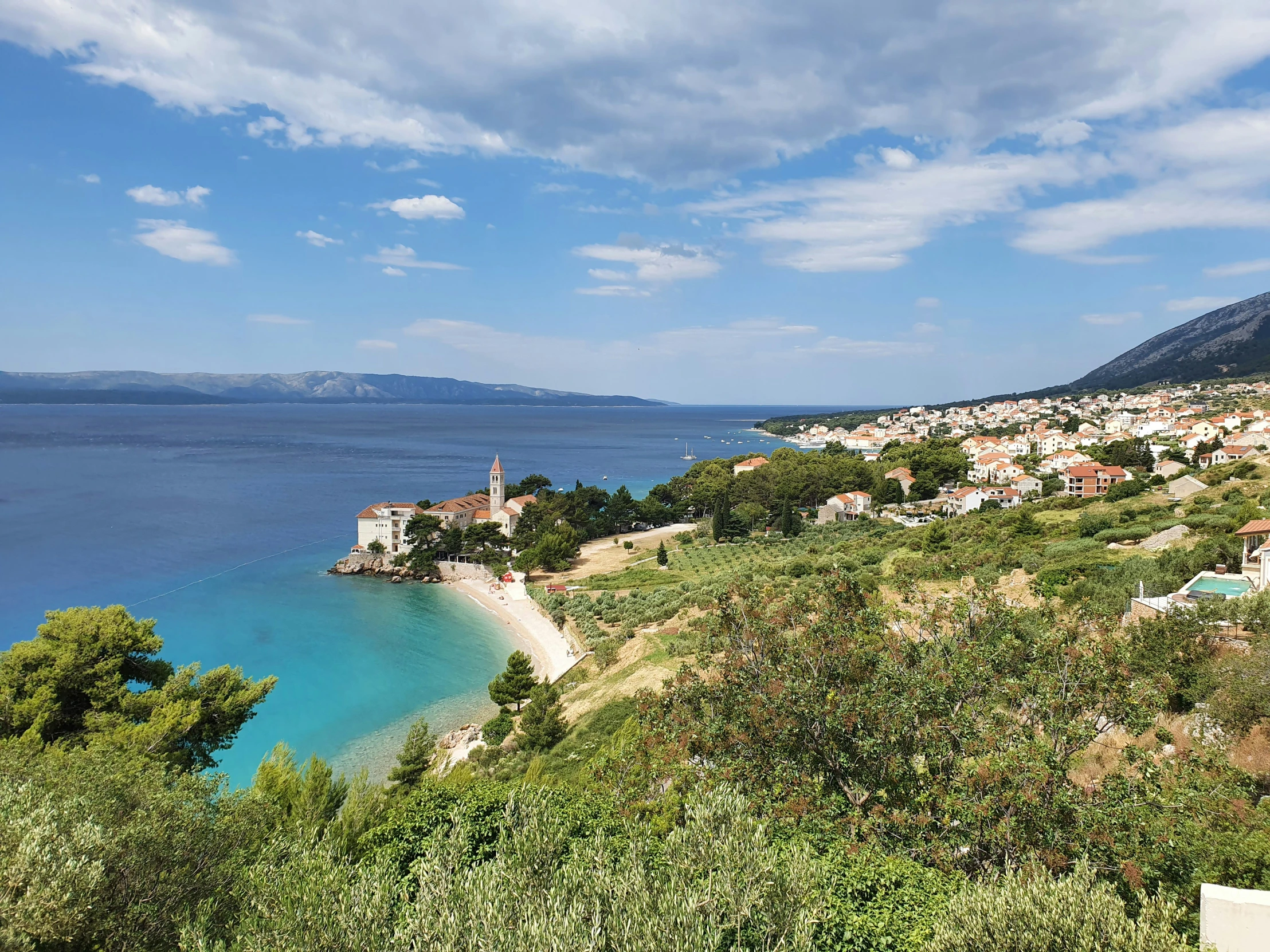 the mountains and buildings overlook a blue sea