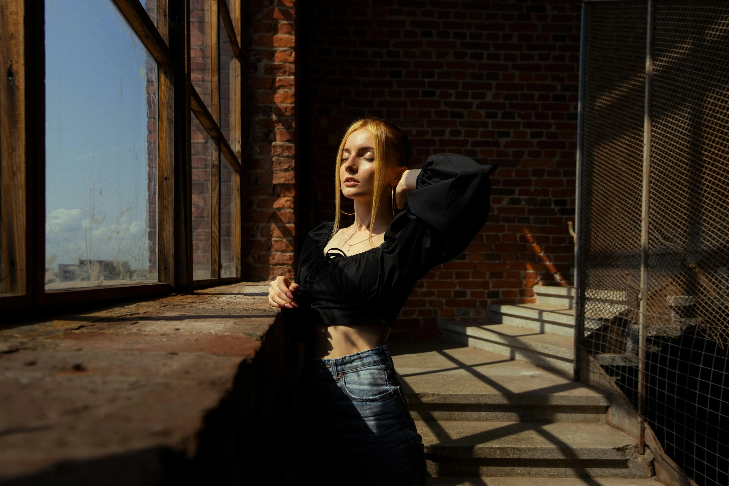 woman standing by brick building holding her jacket in the air