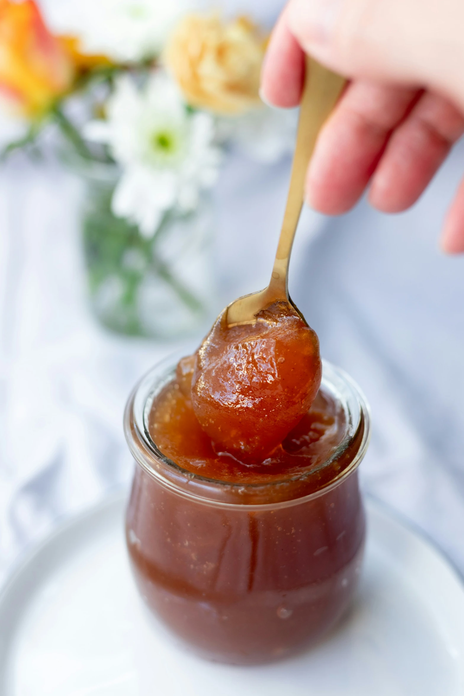 a spoon with a small jar filled with a spoon full of jelly