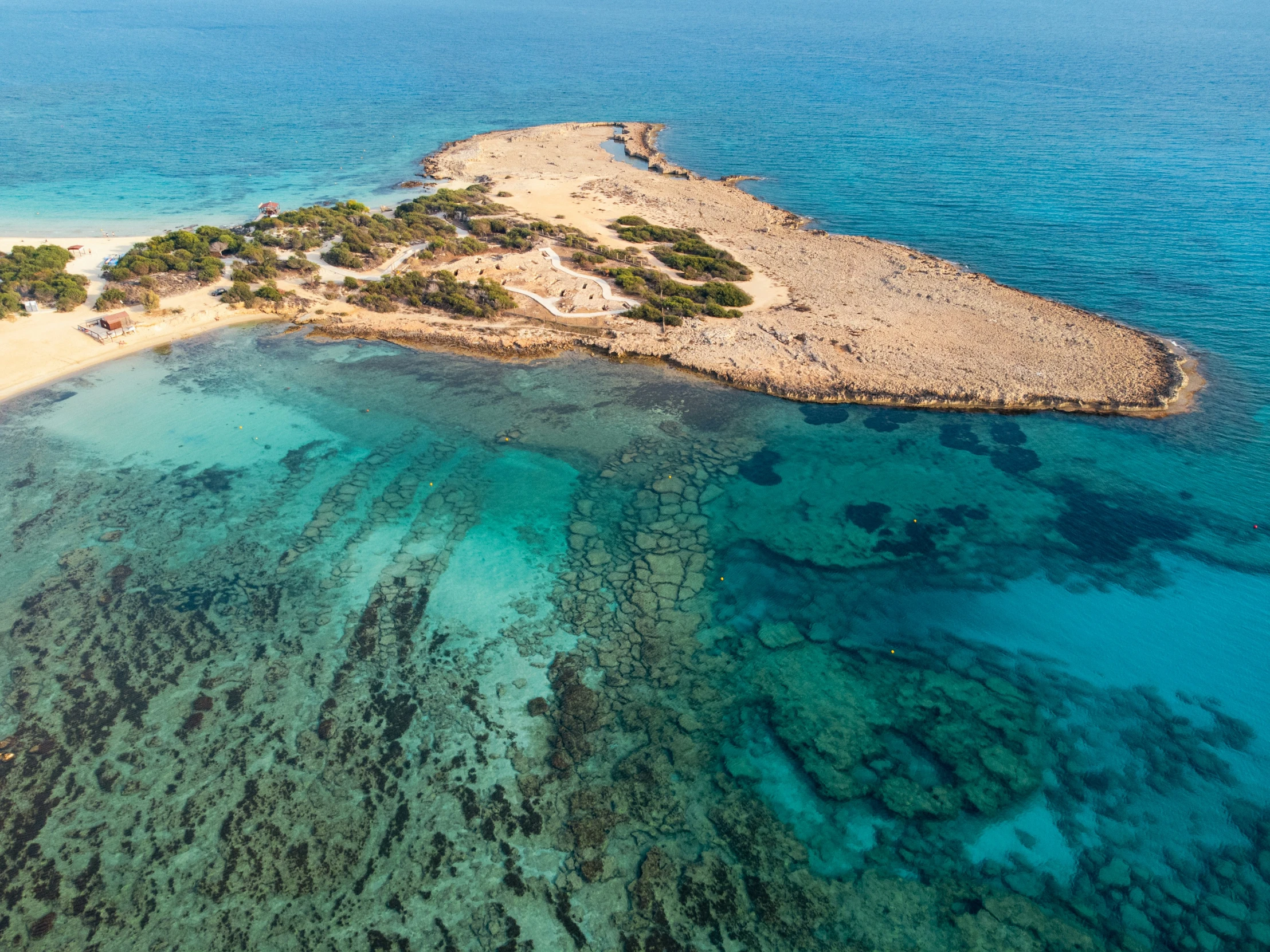 an island is surrounded by shallow clear blue water