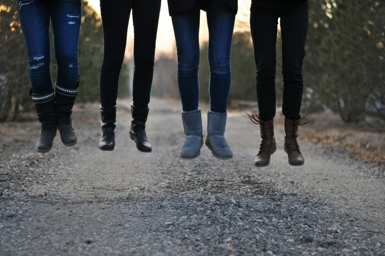 three women standing on a gravel path holding boots