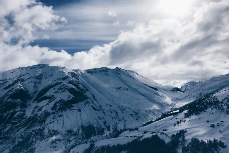 snow is covering a mountain with snow capped trees