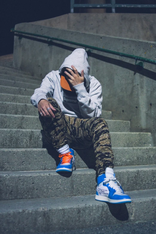 a man with his hands up in the air, sitting on some stairs