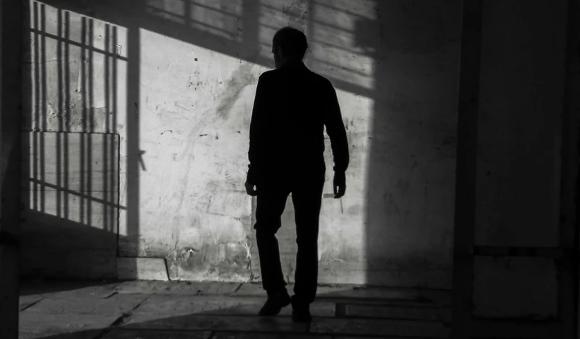 a man is standing in the shadow in the middle of a room