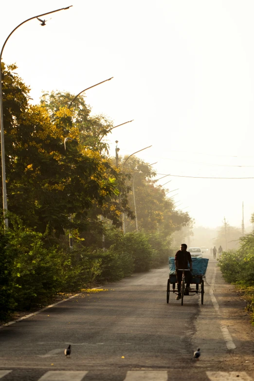 two people are on the back of a blue wagon on a road